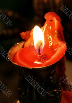 red candle flaming upon dark background