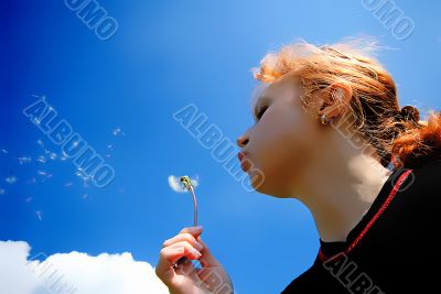  woman blows on  dandelion