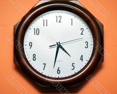Modern clock on orange wall