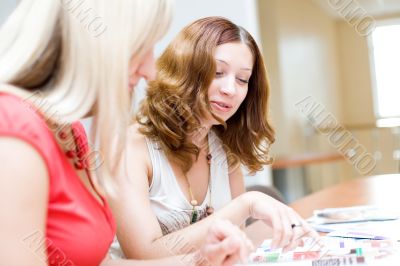 Two beautiful girls discuss the fashion magazine