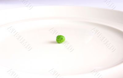 Single green pea on white plate.