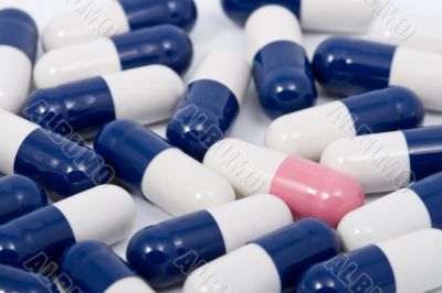 blue and pink capsule pills on white background