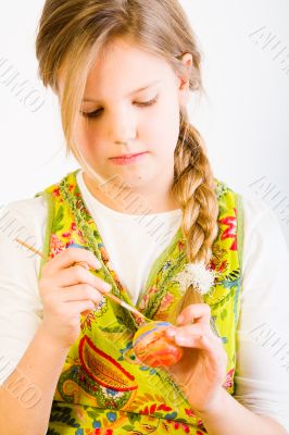 Young girl painting an egg