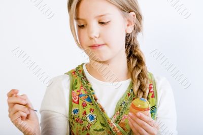 Young girl with painting brush and egg