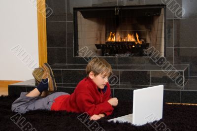 Boy at Fireplace on Computer.