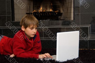 Boy at Fireplace on Computer.