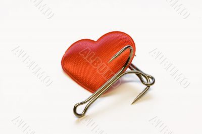 Red heart with a fishing hook on a white background