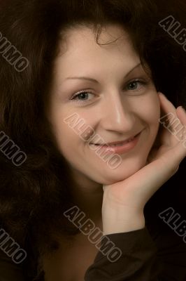 Portrait of the young smiling woman on a dark background.