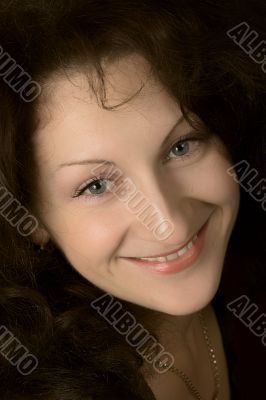 Portrait of the young smiling woman on a dark background.