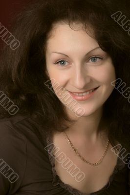 Portrait of the young smiling woman on a dark background.