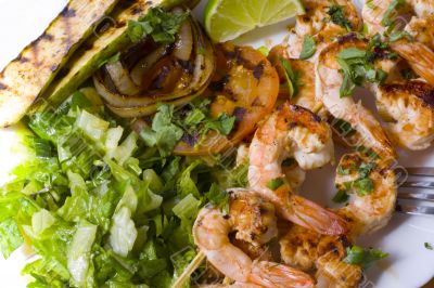 Grilled prawns on bamboo sticks served with salad and grilled ve