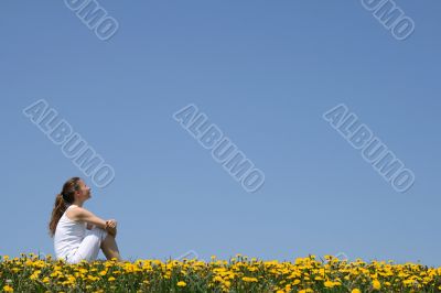 Girl sitting in dandelion field