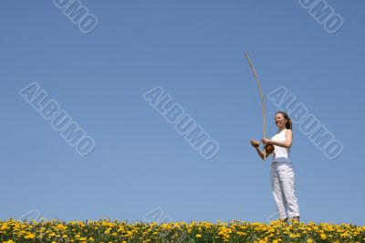 Girl playing berimbau in spring meadow