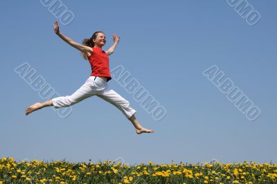 Girl flying in a jump over flowering field
