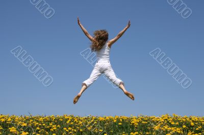 Girl flying in a funny jump over dandelion field