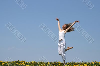 Smiling girl dancing in dandelion field