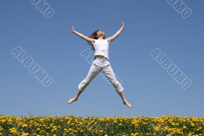 Smiling girl jumping in flowering meadow