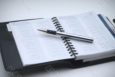 Closeup of a business day planner with a pen - blue tint and vig