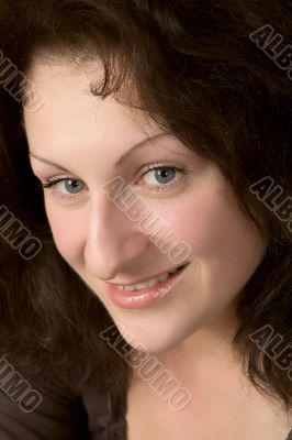 Portrait of the young smiling woman on a dark background.