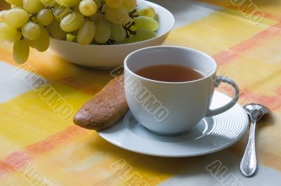 Cup of tea with a biscuit and grapes