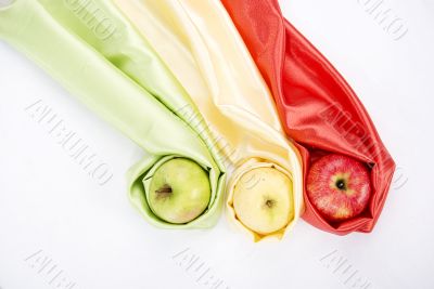 three apples of different colour wrapped in silk