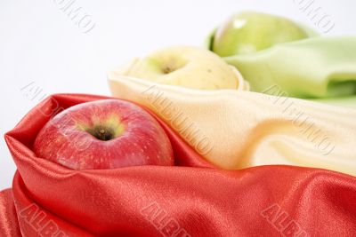 three apples of different colour wrapped in silk