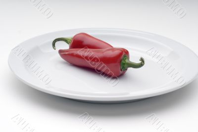 Two red chile peppers on a white plate