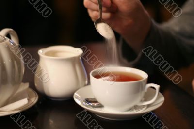 man put sugar into cup of tea