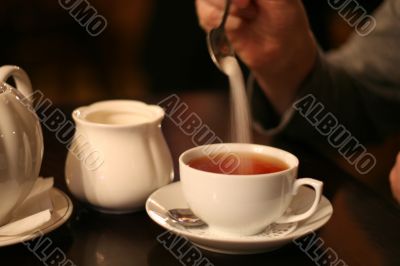 man put sugar into cup of tea