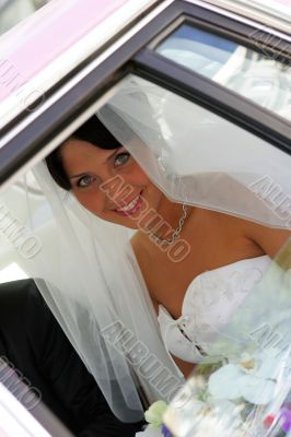 Bride smiling through window of limo