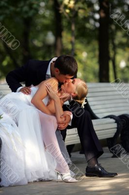 Newlyweds kissing on park bench