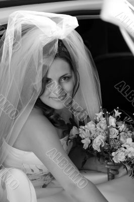 Smiling bride getting out of wedding car limousine