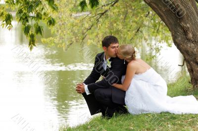 Newlywed couple kissing by lake