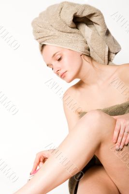 Young woman is shaving her leg