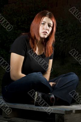 Pensive girl sitting on wood