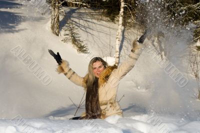 Young beautiful girl on the nature throwing snow.