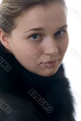 Young beautiful girl in a fur jacket on a white background.