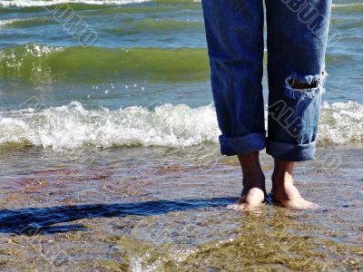 Wet bare feet standing on beach.