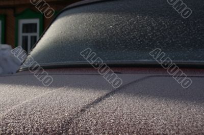 The car covered with frost, against the old house.