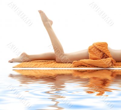 legs of girl with orange towel on white sand 2