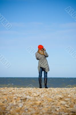 Girl standing on the beach and recording video