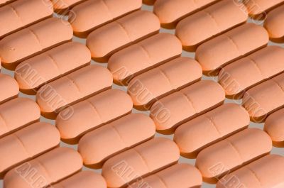 Rows of pink pills over white