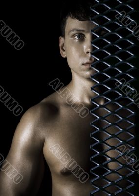 Muscular man behind a lattice