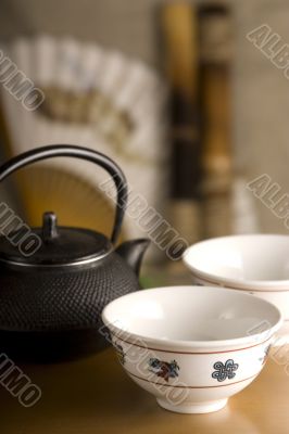 The Chinese teapot, two cups, fan and bamboo on table