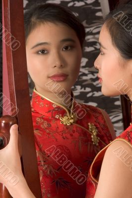 Chinese girl in red cheongsam by mirror