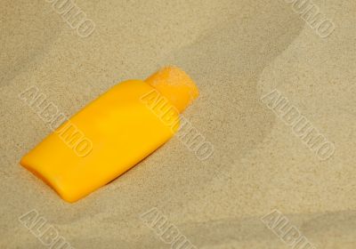 Sunscreen bottle on sand