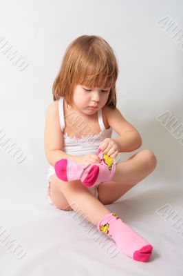 Small girl is puting on the socks