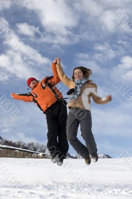 Couple jump over blue sky in winter