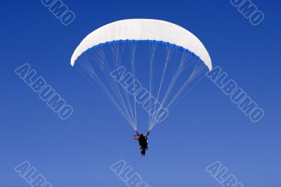 a paraplane flying high up in the deep blue sky