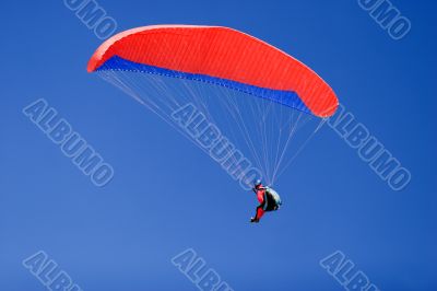 a paraplane flying high up in the deep blue sky
